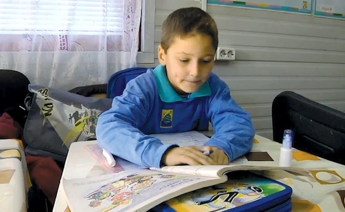 Copiii din Holdea fac carte înconjuraţi de pereţi de tablă