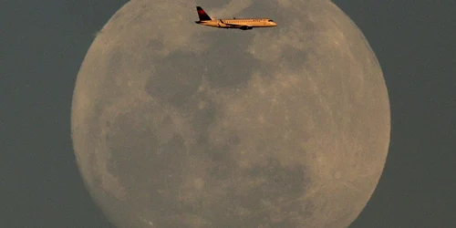 Un avion Delta Airlines care se apropie de Aeroportul Internaţional Sky Harbor trece pe lângă luna plină în Phoenix Arizona FOTO AP