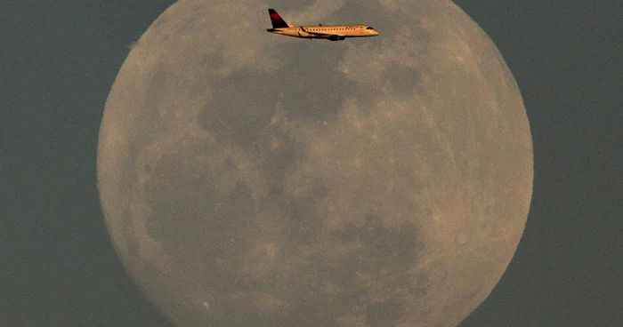 Un avion Delta Airlines care se apropie de Aeroportul Internaţional Sky Harbor trece pe lângă luna plină în Phoenix Arizona FOTO AP