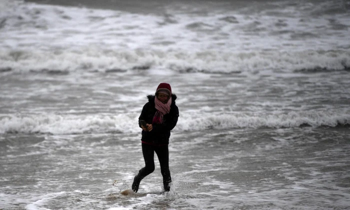 O femeie se plimbă pe plajă, în Bournemouth, Marea Britanie, în timpul furtunii Dennis care a lovit Regatul Unit Foto EPA EFE