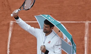 Sârbul Novak Djokovic intră pe teren cu o umbrelă înainte de a relua a patra rundă a meciului cu spaniolul Roberto Bautista Agut la French Open de la Roland Garros în Paris Franţa FOTO AP