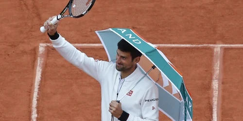 Sârbul Novak Djokovic intră pe teren cu o umbrelă înainte de a relua a patra rundă a meciului cu spaniolul Roberto Bautista Agut la French Open de la Roland Garros în Paris Franţa FOTO AP