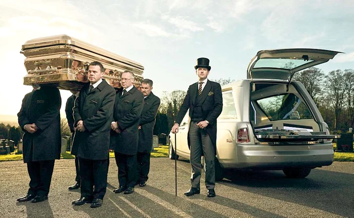 Patronul companiei angajează special oameni să care coşciugul, pentru a feri rudele de traume