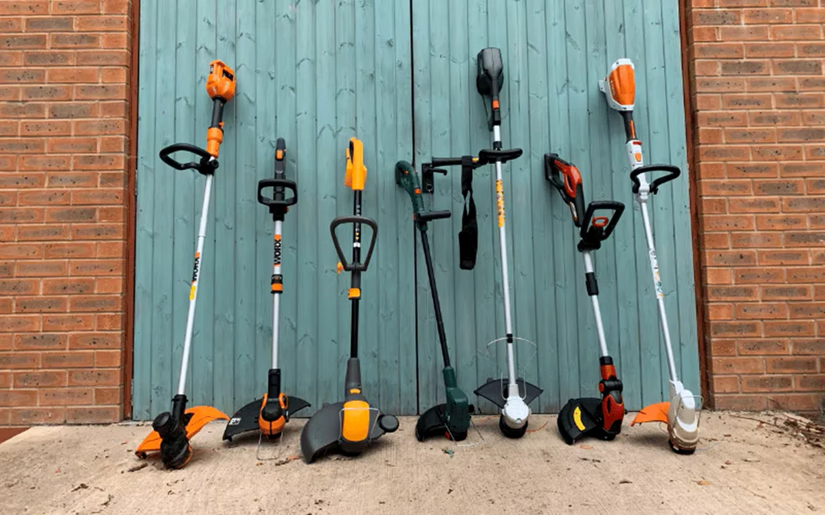 Colecție de coase electrice expuse pe ușa unei construcții pentru depozitare Foto The English Garden