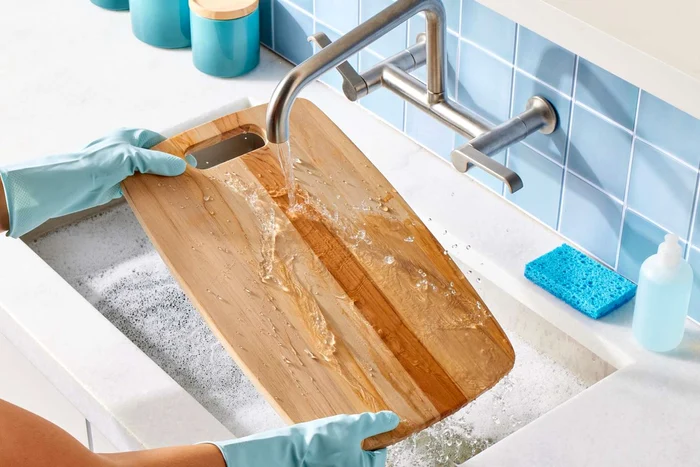 Tocător din lemn spălat cu apă într-o chiuvetă Foto Real Simple