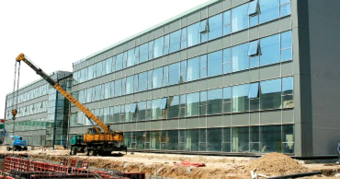 O macara plasează piese de construcție pentru ridicarea unui depozit lângă o fabrică