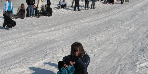 Tinerii care nu au sanie folosesc pe pârtie un sac din plastic 