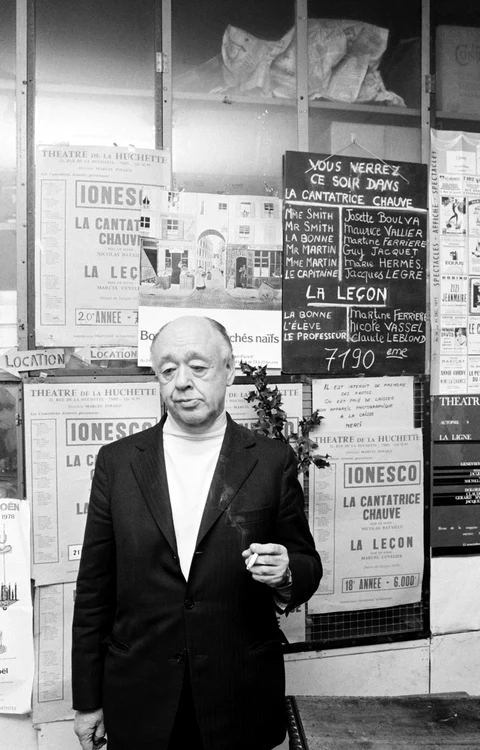 Eugene Ionesco în fața unui teatru din Franța, având în spate afișe cu spectacole după piesele de te