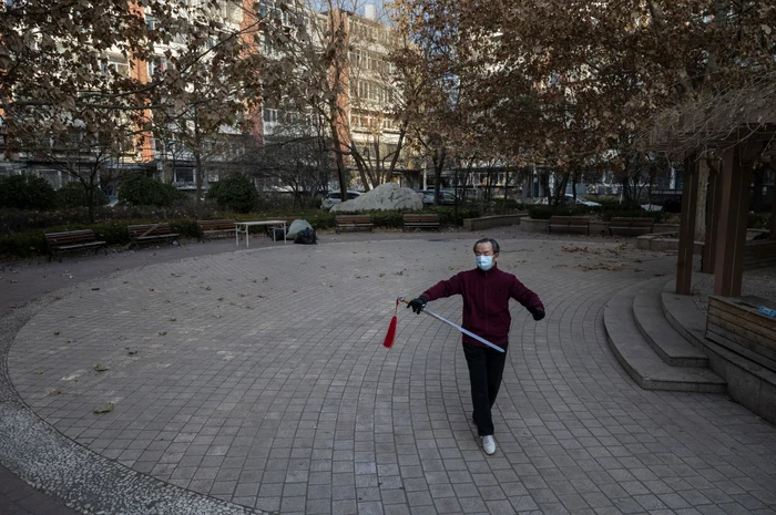 Un bărbat poartă mască în timp ce practică Tai Chi într-un cartier redeschis FOTO Getty Images