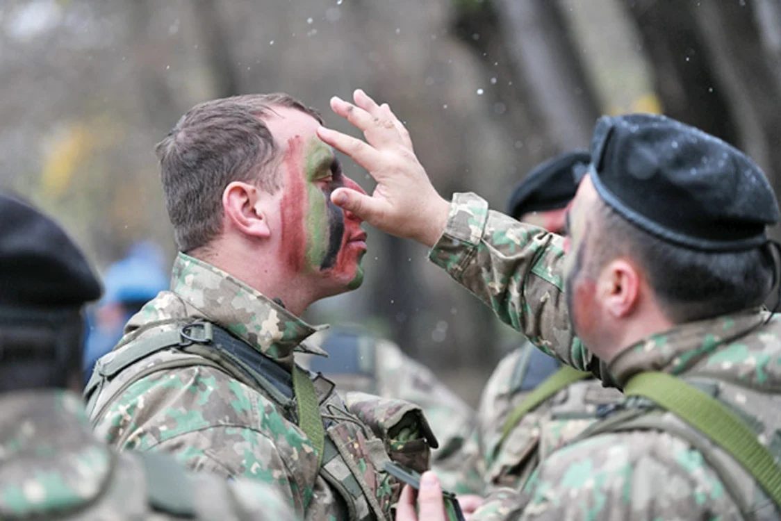 Un militar își ”machiază”  camaradul pentru paradă 