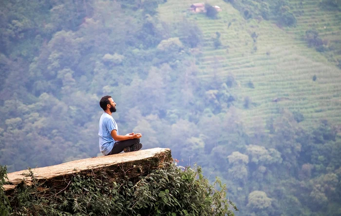 bărbat care meditează pe deal