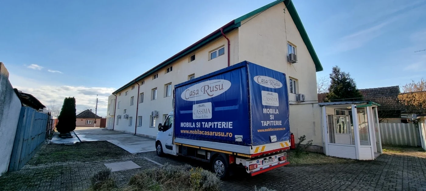 Camionetă pe care scrie Casa Rusu la intrarea în fabrica de mobilă