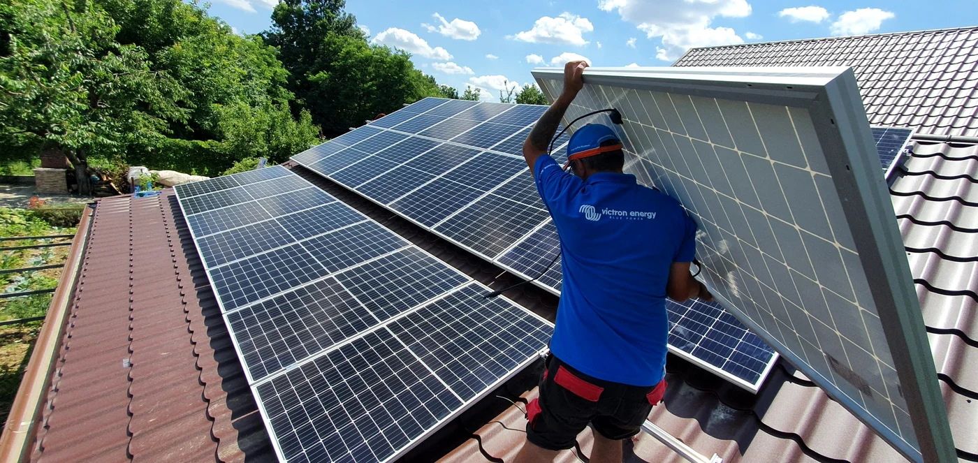 Un muncitor instaleayă panouri fotovoltaice pe un acoperiş